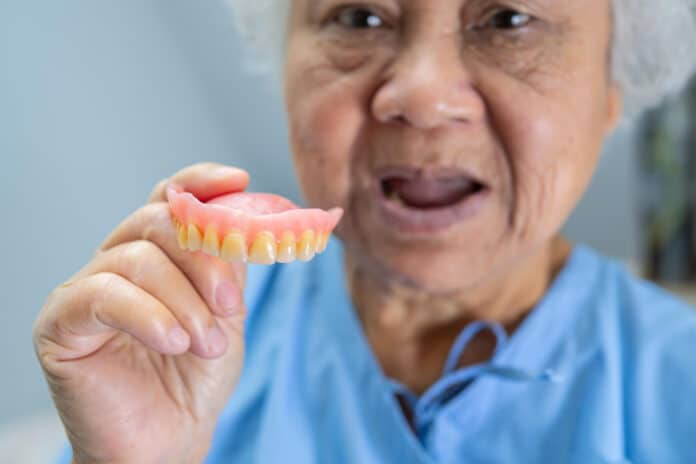 Asian senior or elderly old woman patient holding to use denture in nursing hospital ward healthy strong medical concept