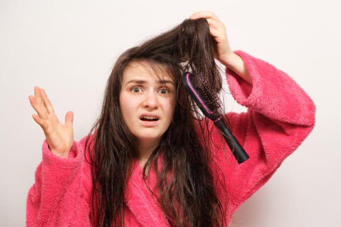 A woman with wet long tangled hair tries to comb