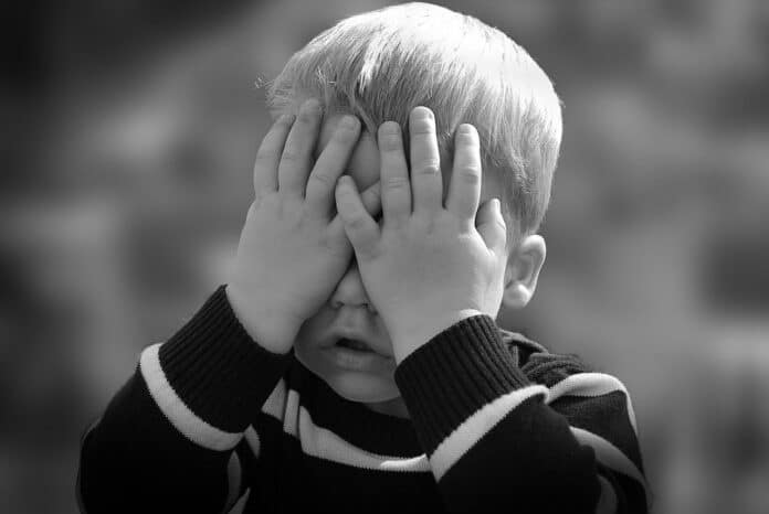 A boy putting his hand on his face.